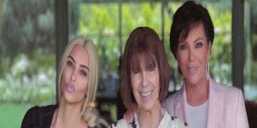 This photo shows Kim, her daughter, Mary Jo and Kris posing together smiling. They are standing by some bright pink flowers.