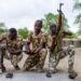 Three Nigerian soldiers wearing army fatigues appear to load their guns