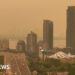 Orange haze fills the sky over a skyline of tall buildings and a highway in Toronto.