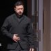 Zelensky, wearing a dark suit, walking through a doorway