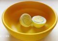A boiled egg placed in a yellow plastic bowl