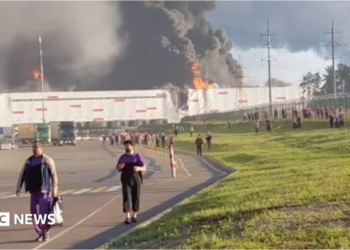 people walk away from a burning warehouse
