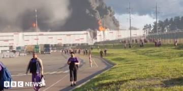 people walk away from a burning warehouse
