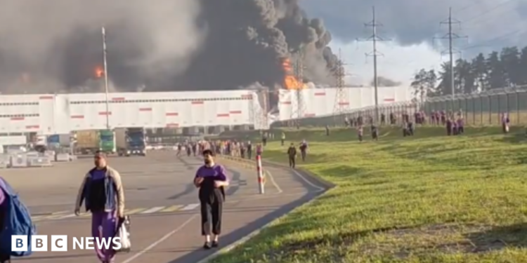 people walk away from a burning warehouse
