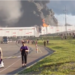 people walk away from a burning warehouse