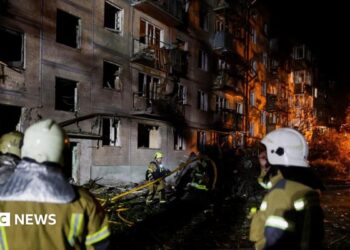 Firefighters work at the site of an apartment building hit by a Russian missile strike in Kyiv