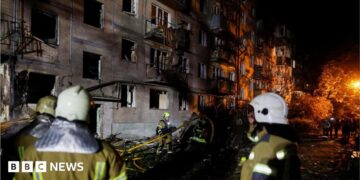 Firefighters work at the site of an apartment building hit by a Russian missile strike in Kyiv