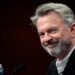 Sam Neill walking through a Jurassic forest, leading two children