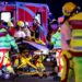 A number of emergency services personnel standing near an ambulance, with a person on a stretcher