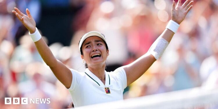 Filipina tennis player Alexandra Eala raises his arms after a Wimbledon match, net in front of her and a blurred image of the crowd in the background.