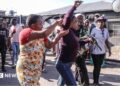 A woman, allegedly an undocumented migrant, is confronted as protesters search for foreign nationals during an anti-migrant march in Alexandra on 9 July 2026.
