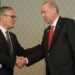 Sir Keir and Erdogan, both wearing dark suits, shake hands. Behind them are the Union Jack and Turkish national flag.