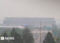 Smoke from Canadian wildfires shrouds MetLife Stadium, host of the 2026 FIFA World Cup final, as hazy orange skies reduce visibility over a busy highway in New Jersey.