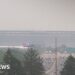 Smoke from Canadian wildfires shrouds MetLife Stadium, host of the 2026 FIFA World Cup final, as hazy orange skies reduce visibility over a busy highway in New Jersey.