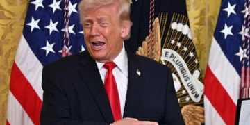S President Donald Trump (L) reacts as US bobsledder Kaillie Armbruster Humphries announces she is awarding him with an Ikkos award during a Women's History Month event in the East Room of the White House in Washington, DC, on March 12, 2026. Medal-winning team USA athletes can award an Ikkos award to recognize people who have been supportive in their journey to the Games. (Photo by Jim WATSON / AFP via Getty Images)