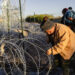 A group of migrants make their way along miles of concertina wire deployed by the Texas National Guard under Operation Lone Star in El Paso, Texas on April 2, 2024.