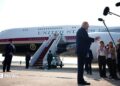 Trump stands in front of Qatari-gifted Air Force One and speaks to reporters who are holding boom microphones
