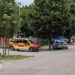 Emergency service vehicles with flashing lights outside a school building, the road is quiet.