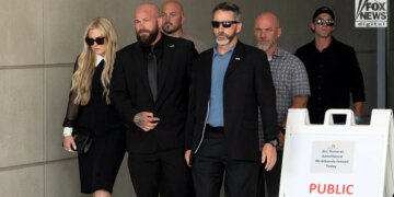 Erika Kirk, left, wearing a black dress and sunglasses as she leaves the Fourth District Courthouse in Provo