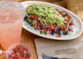 A chicken bowl from Chipotle with a drink and a dip.