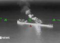 A still image of an oil tanker under attack from a drone in a black and while nighttime image