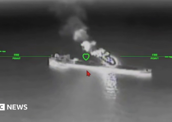 A still image of an oil tanker under attack from a drone in a black and while nighttime image