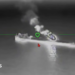 A still image of an oil tanker under attack from a drone in a black and while nighttime image