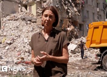 Sarah Rainsford standing in front of rubble