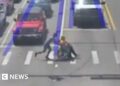 Man dressed as Spider-Man pushes wheelchair user across a crossing