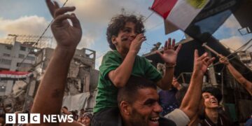 Boy sits on his father's shoulders