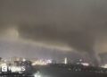 A giant tornado sweeping a city in the night, with the skyline of a city behind it