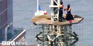 A man and a woman are seen during a proposal on top of the top of the Empire State Building.
