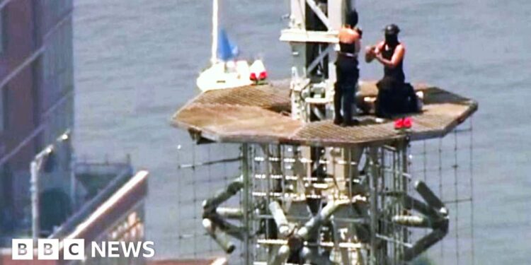 A man and a woman are seen during a proposal on top of the top of the Empire State Building.