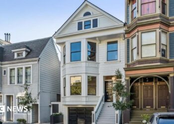 Three homes on a residential street in San Francisco. The three floor homes look clean and well maintained with well-trimmed plants and trees outside.