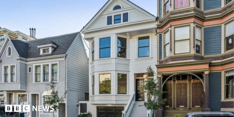 Three homes on a residential street in San Francisco. The three floor homes look clean and well maintained with well-trimmed plants and trees outside.