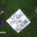 A banner saying "Las Malvinas Son Argentinas" is on the ground of a pitch with three players standing around it