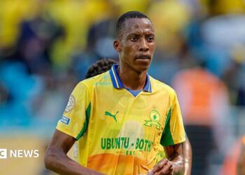 Footballer Divine Lunga is seen during a match in a yellow and green Mamelodi Sundowns shirt