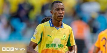 Footballer Divine Lunga is seen during a match in a yellow and green Mamelodi Sundowns shirt