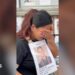 Dolma Gurung crying into her hand while holding a poster of her missing husband.