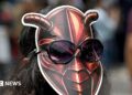 A woman wearing a cockroach mask on the back of her head