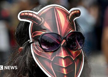 A woman wearing a cockroach mask on the back of her head
