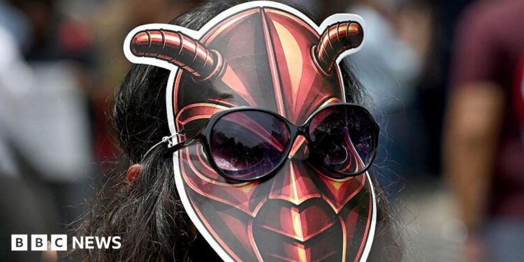A woman wearing a cockroach mask on the back of her head