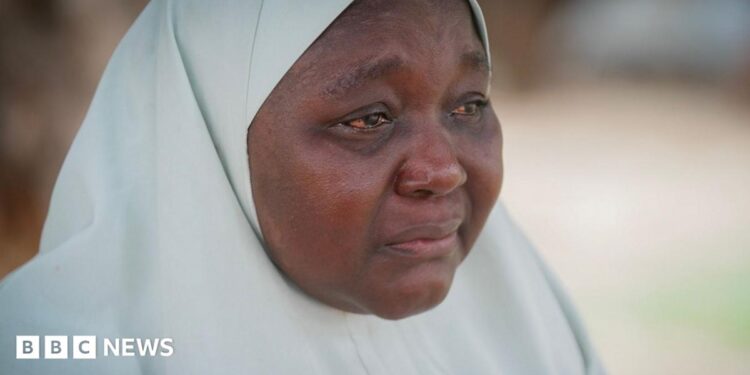 A woman wearing a white hijab, her eyes red from crying
