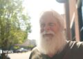 David Carter sports a full white beard - which helps him play Santa at Christmas - as he stands on a main street in downtown Kingstport