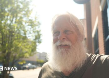 David Carter sports a full white beard - which helps him play Santa at Christmas - as he stands on a main street in downtown Kingstport