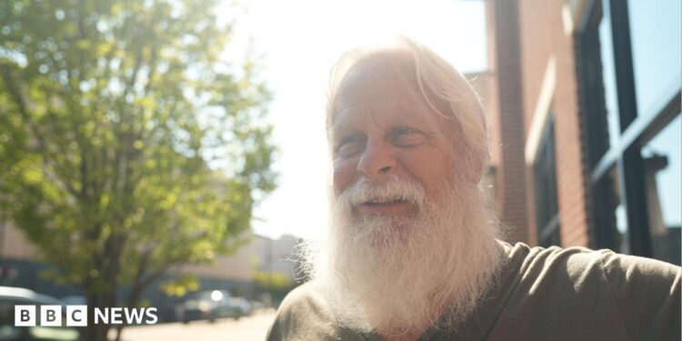 David Carter sports a full white beard - which helps him play Santa at Christmas - as he stands on a main street in downtown Kingstport