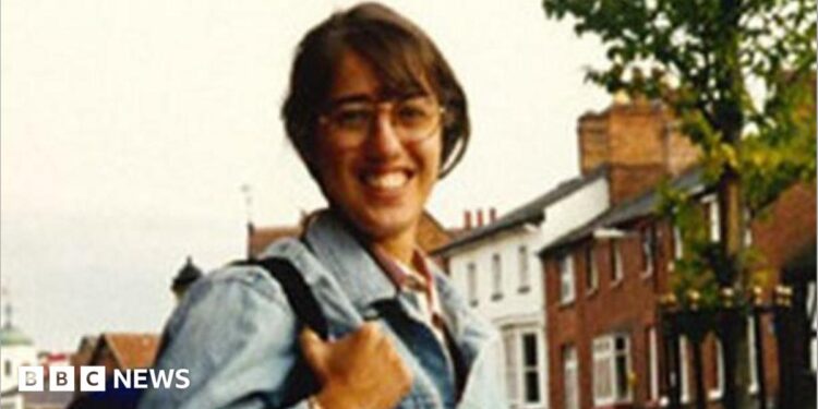 A young woman smiles wearing a denim jacket and glasses in a clearly old colour picture