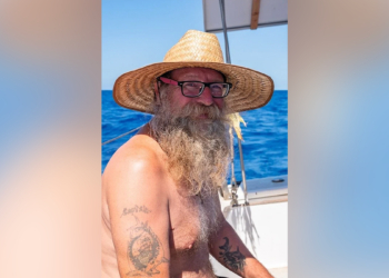 Donald Steven Lang aboard a sailboat wearing a straw hat
