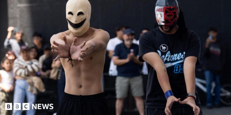 Two young men in masks hold their hands out.
