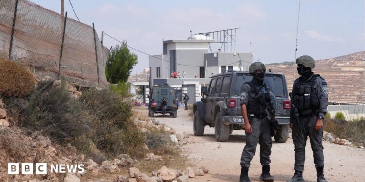 Members of the Israeli security forces stand guard near a Palestinian house, which was besieged by Israeli settlers, in Qusra